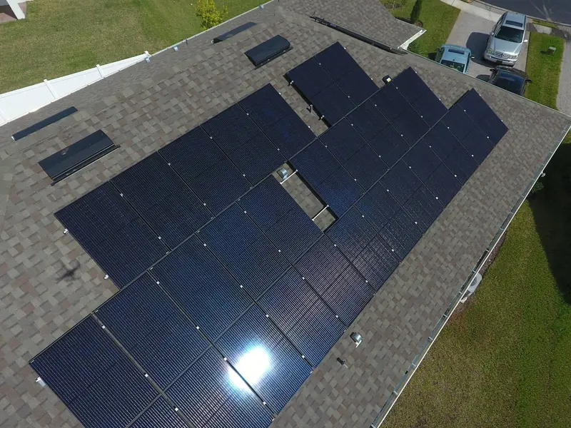 Close aerial view of dark solar panels covering a shingle roof