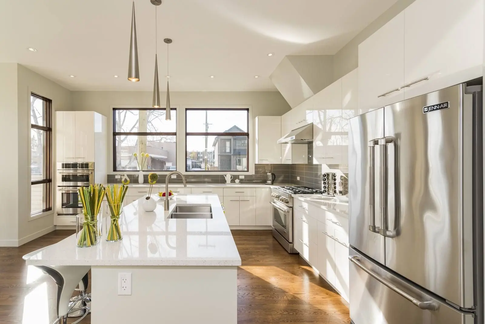 Bright modern kitchen with white cabinets, a large island and stainless steel appliances