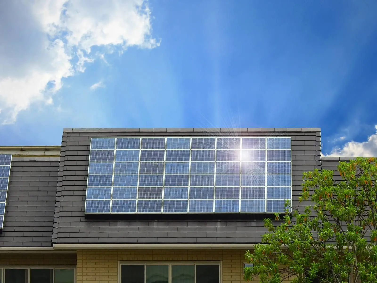 Solar panels on a tiled roof with sunlight shining from a blue sky
